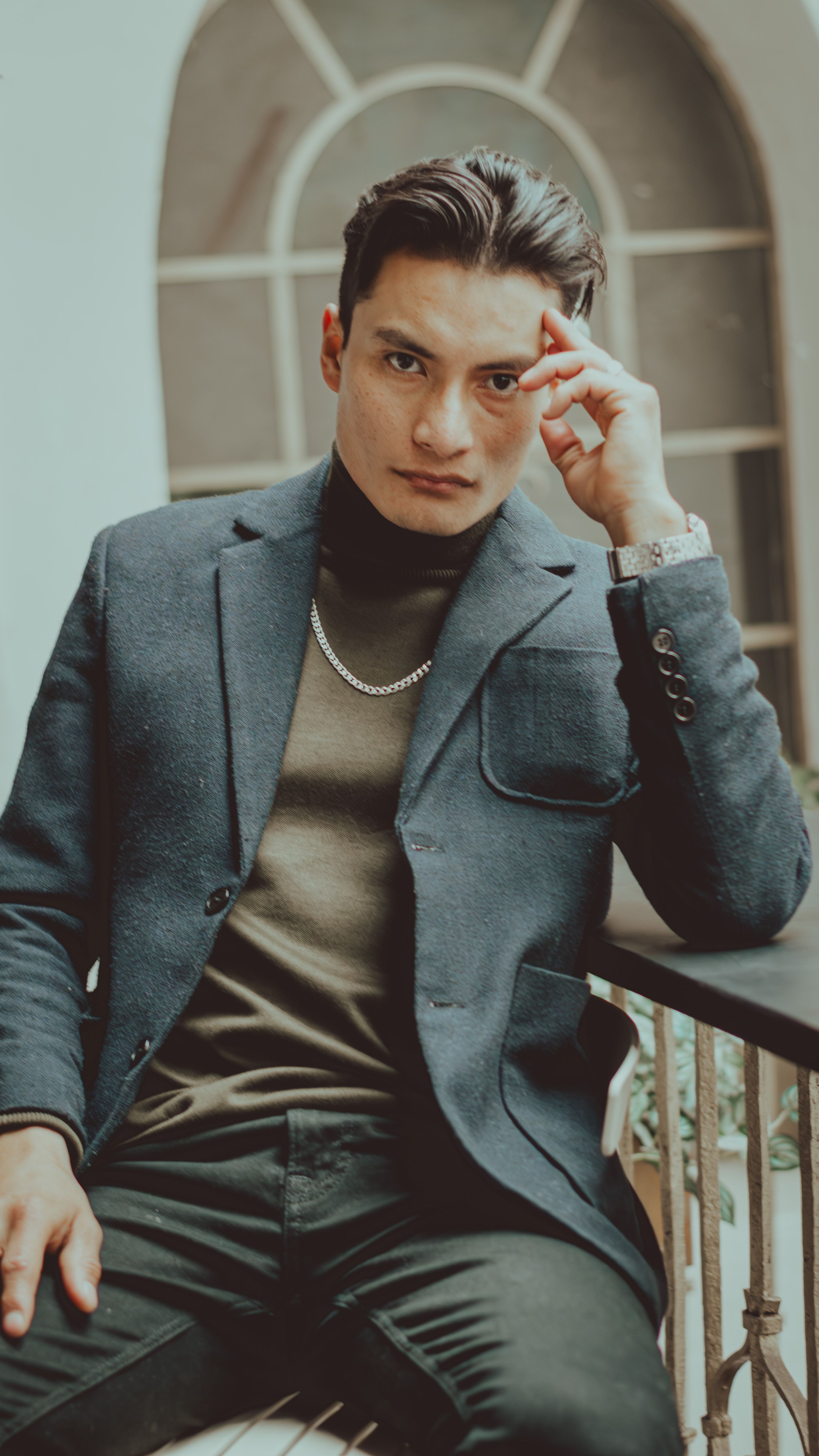 Chic young man in a stylish blazer posing thoughtfully indoors.