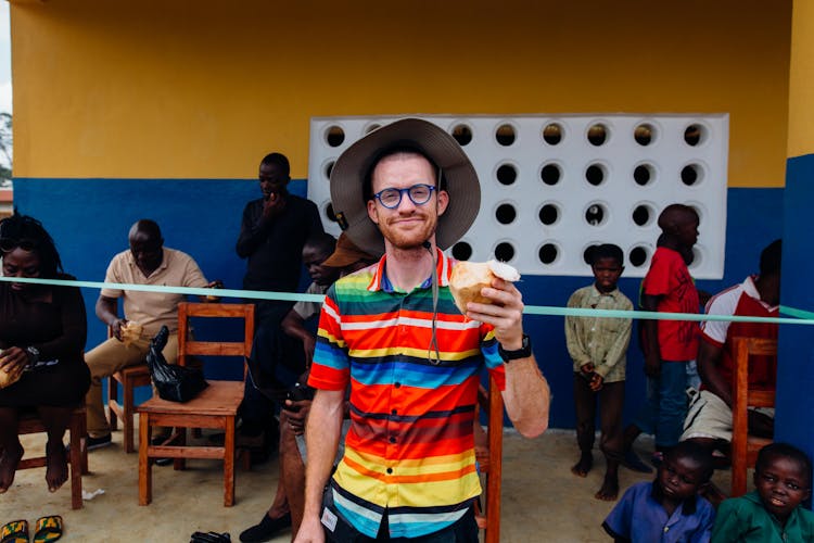 Smiling Man Holding Coconut Standing Near People