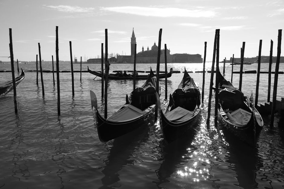 Elegant gondolas anchored in a Venice canal, with iconic skyline in the background.