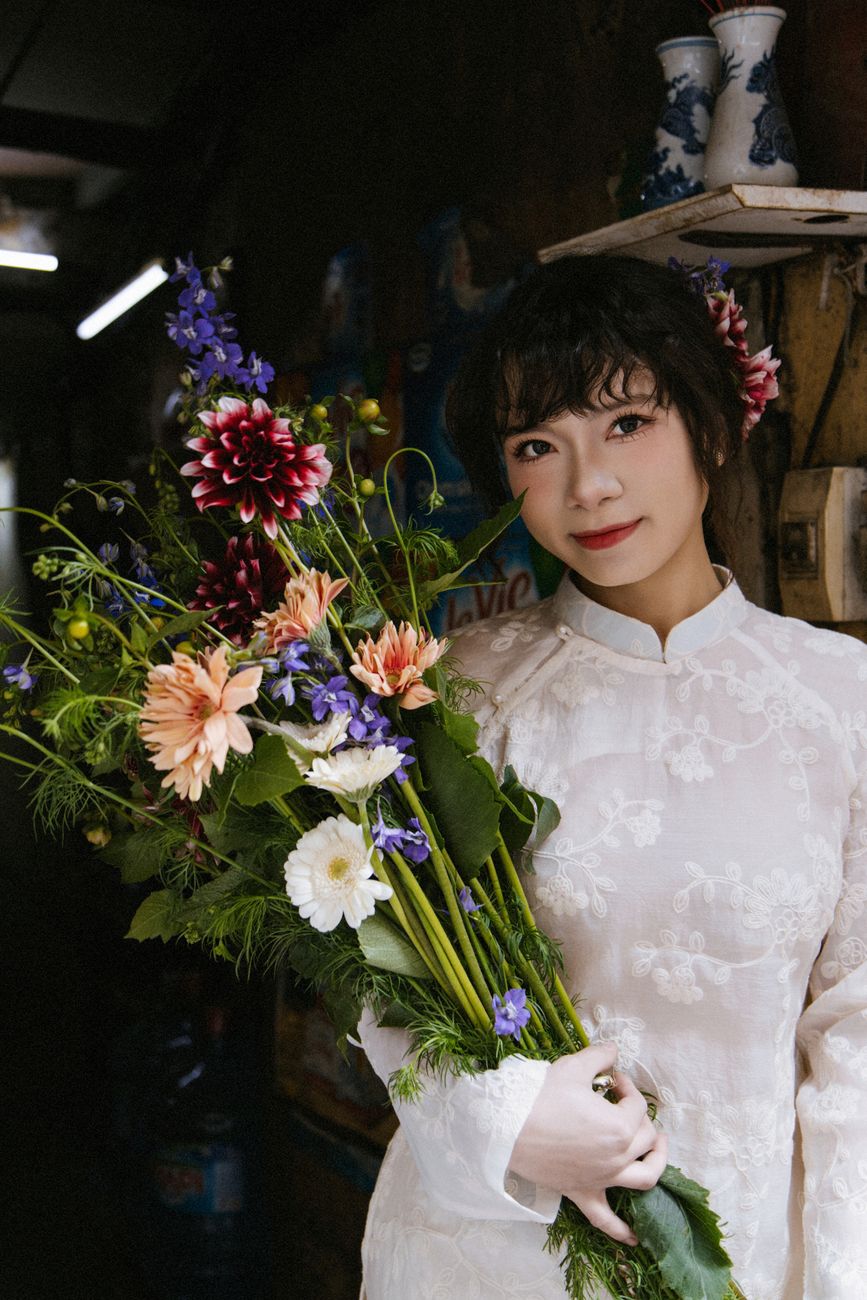 Portrait of a woman in Hanoi, Vietnam, holding a vibrant bouquet, showcasing Vietnamese culture.