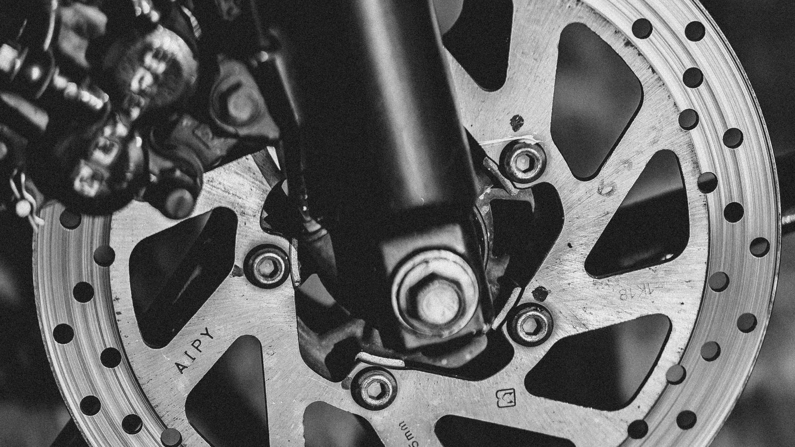 Detalhe do disco de freio de uma moto usada sendo inspecionado para identificar riscos e desgaste