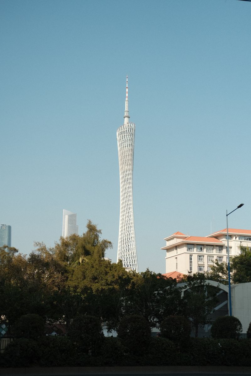Canton Tower rising above trees under a clear sky in Guangzhou