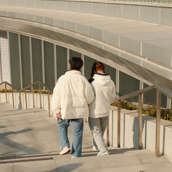 Couple in winter jackets walking down urban stairs, photo by Muhamad Guruh Budi Hartono on Pexels