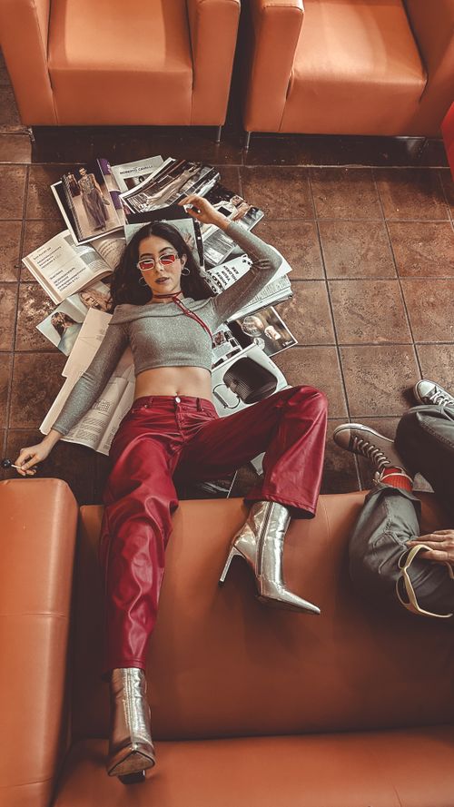 Free Young woman in stylish outfit lounges amidst magazines indoors. Stock Photo