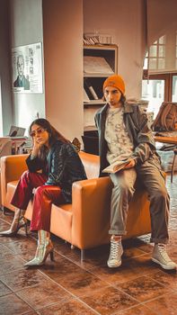 Fashionable young adults in a lounge setting with vibrant attire and relaxed poses.