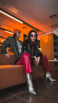 Stylish young adults in chic attire posing in modern urban environment.