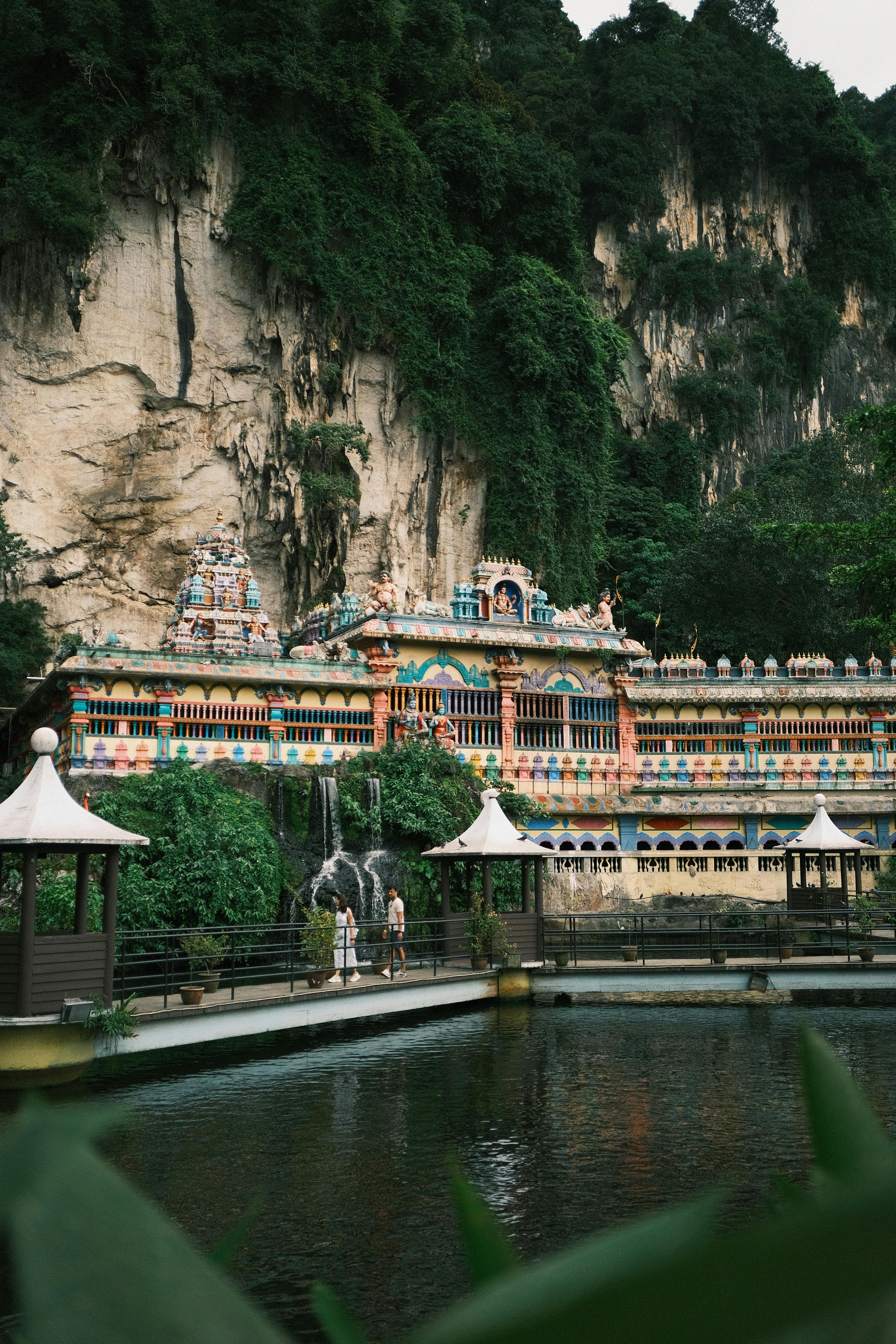 A stunning view of a Hindu temple at Batu Caves set against lush greenery and rock formations.