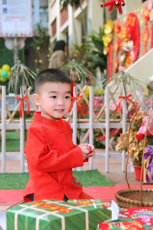 Free A young boy wearing a red traditional outfit celebrates Lunar New Year outdoors. Stock Photo
