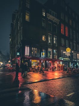 Vibrant nightlife in Amsterdam with illuminated streets and Dutch architecture. Captured on a rainy night.