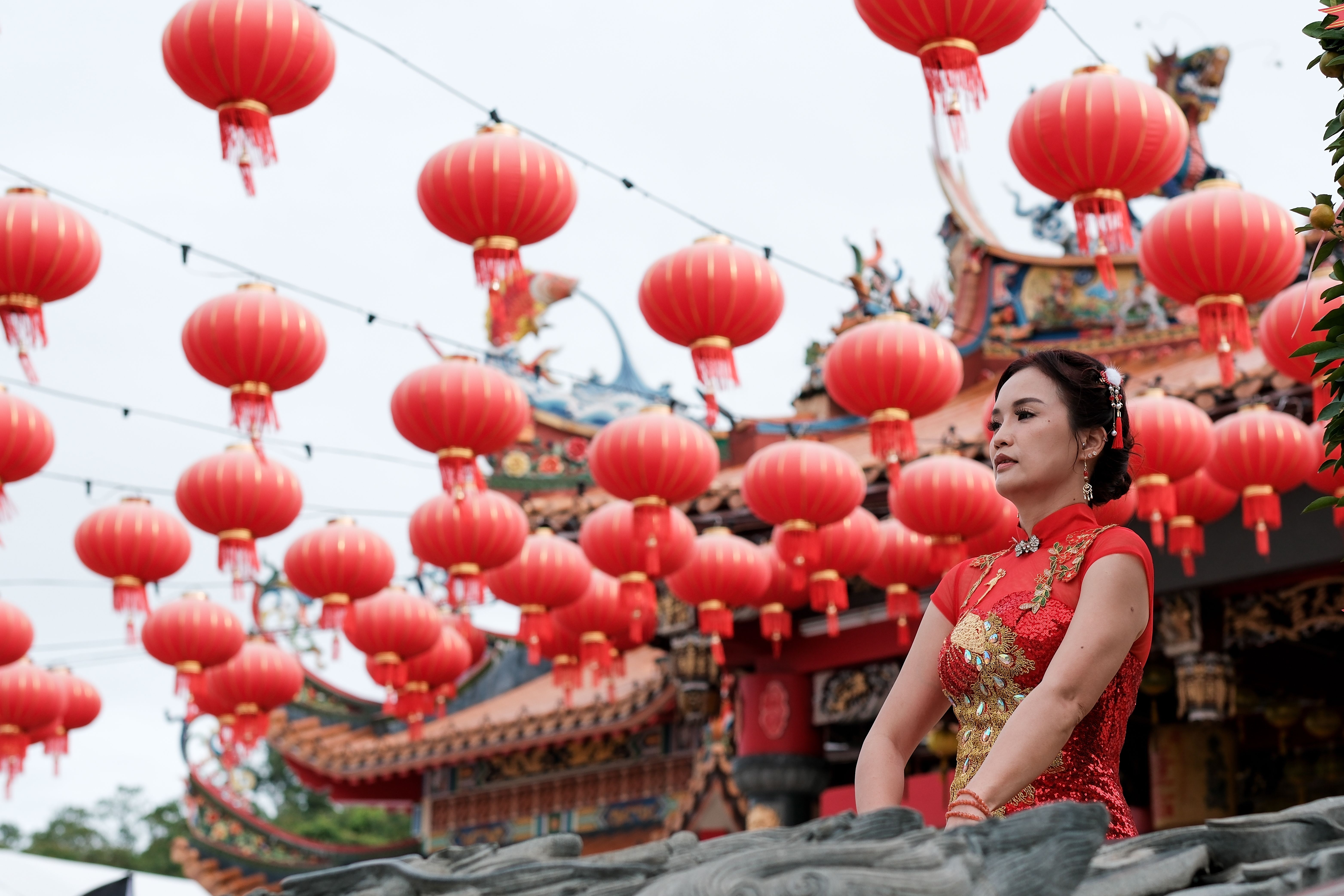 Woman in red qipao at a Chinese New Year lantern festival outdoors.