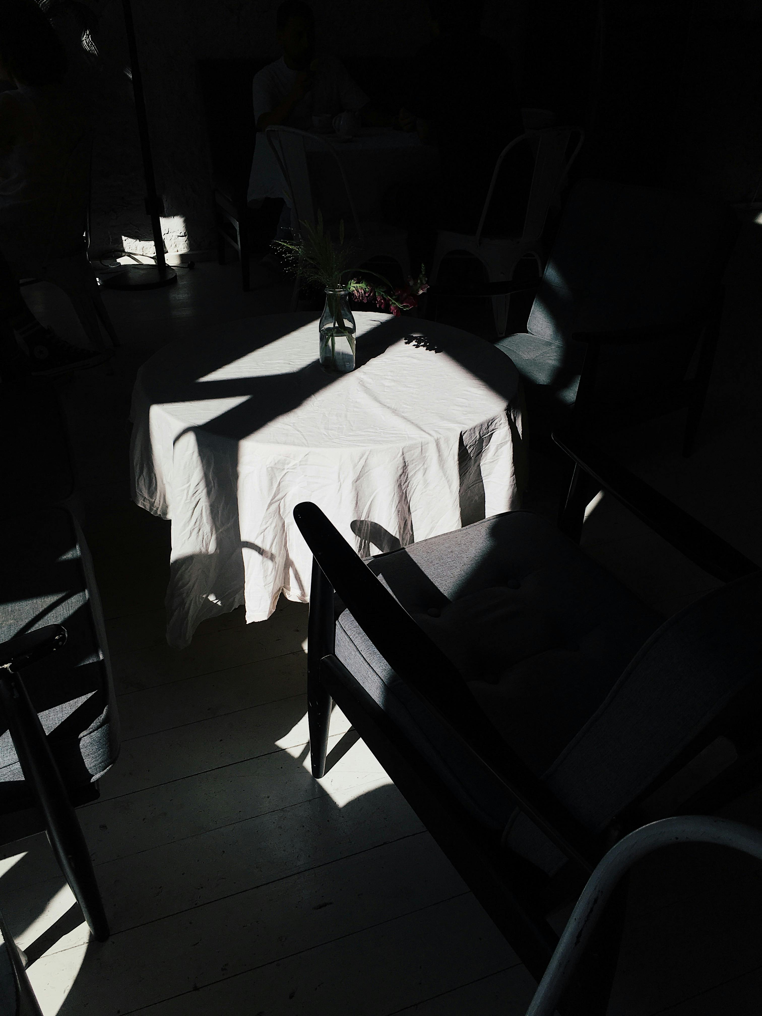 Artistic indoor scene of chairs and table with dramatic sunlight and shadows.