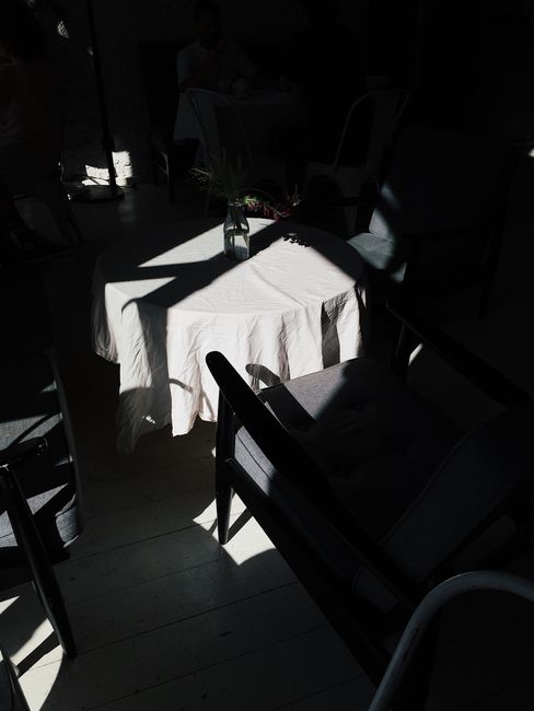 Artistic indoor scene of chairs and table with dramatic sunlight and shadows.