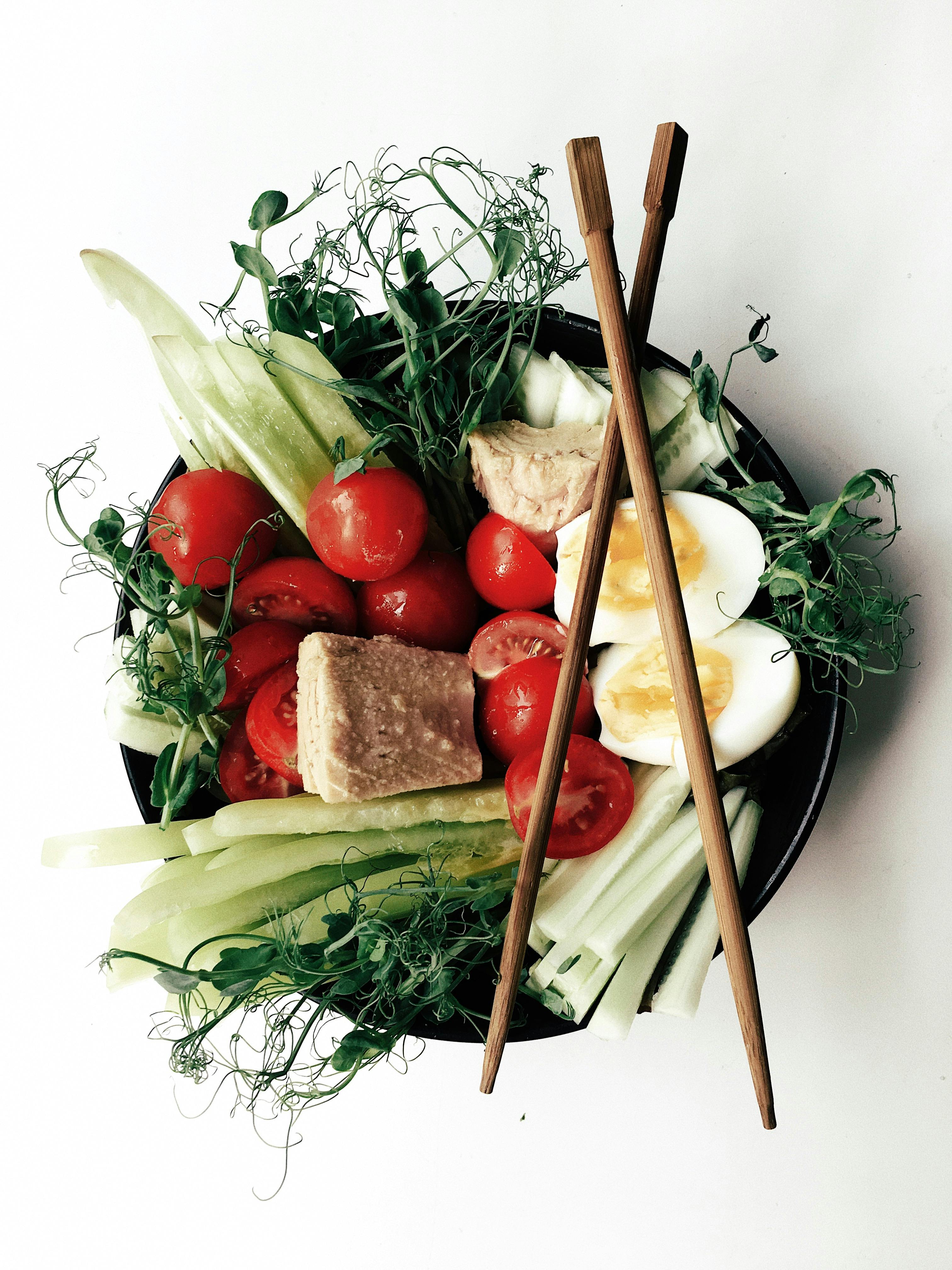 新鲜健康的沙拉碗，用筷子优雅地呈现，配有樱桃番茄、黄瓜、煮鸡蛋和豆芽