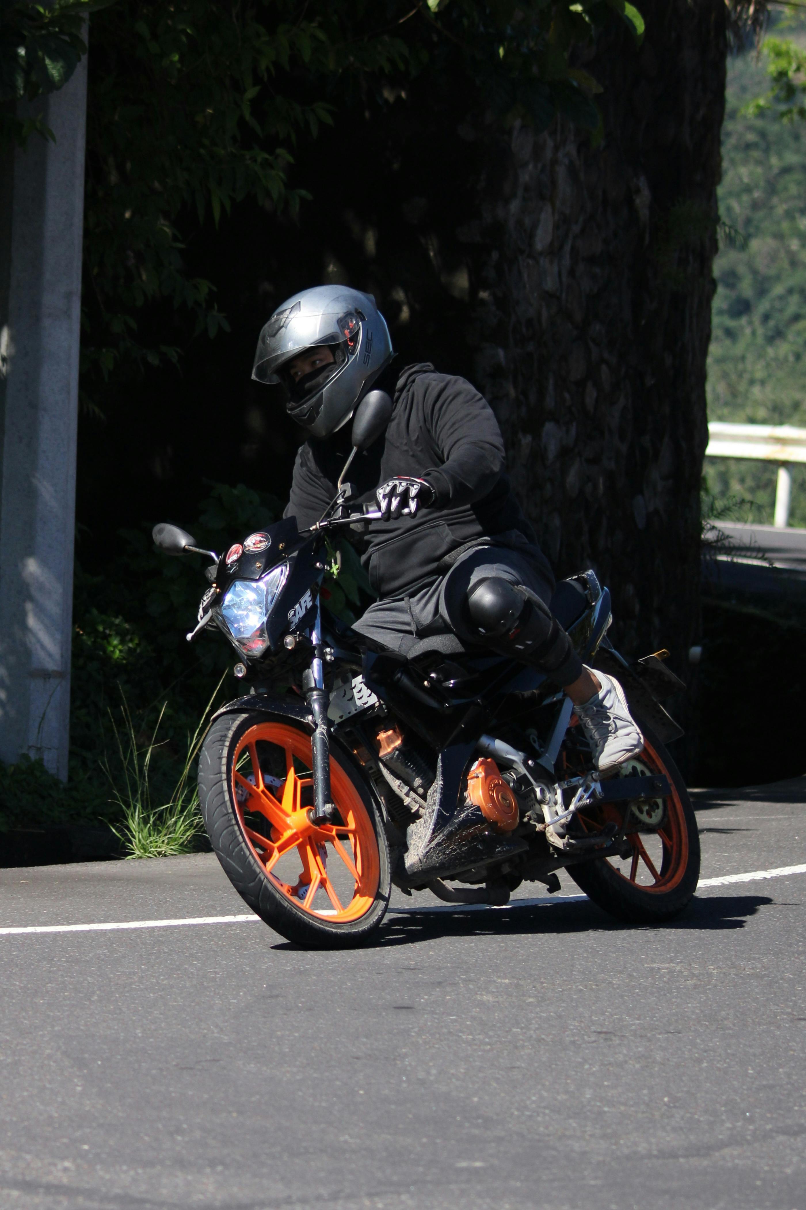 Motorcyclist skillfully leans into a sharp curve showing dynamic movement on a sunny day.