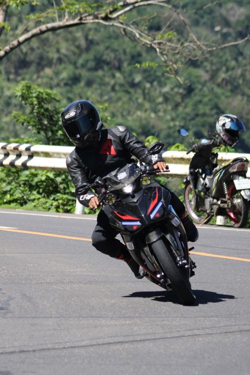 Free Biker in protective gear skillfully steering a motorcycle on a winding road on a sunny day. Stock Photo