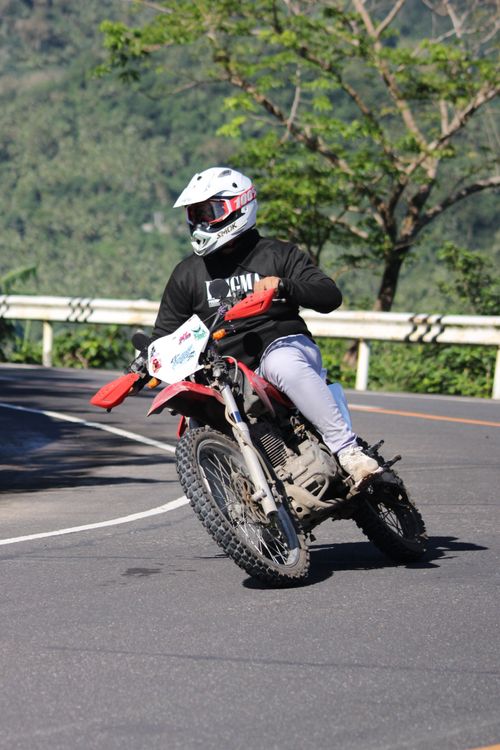 Free Motorcyclist in helmet leaning into a sharp mountain curve for adventurous ride. Stock Photo