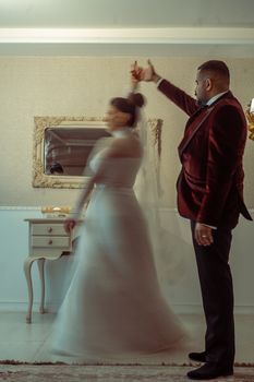 Bride and groom share a graceful dance in an elegant interior. Captures romance and luxury.