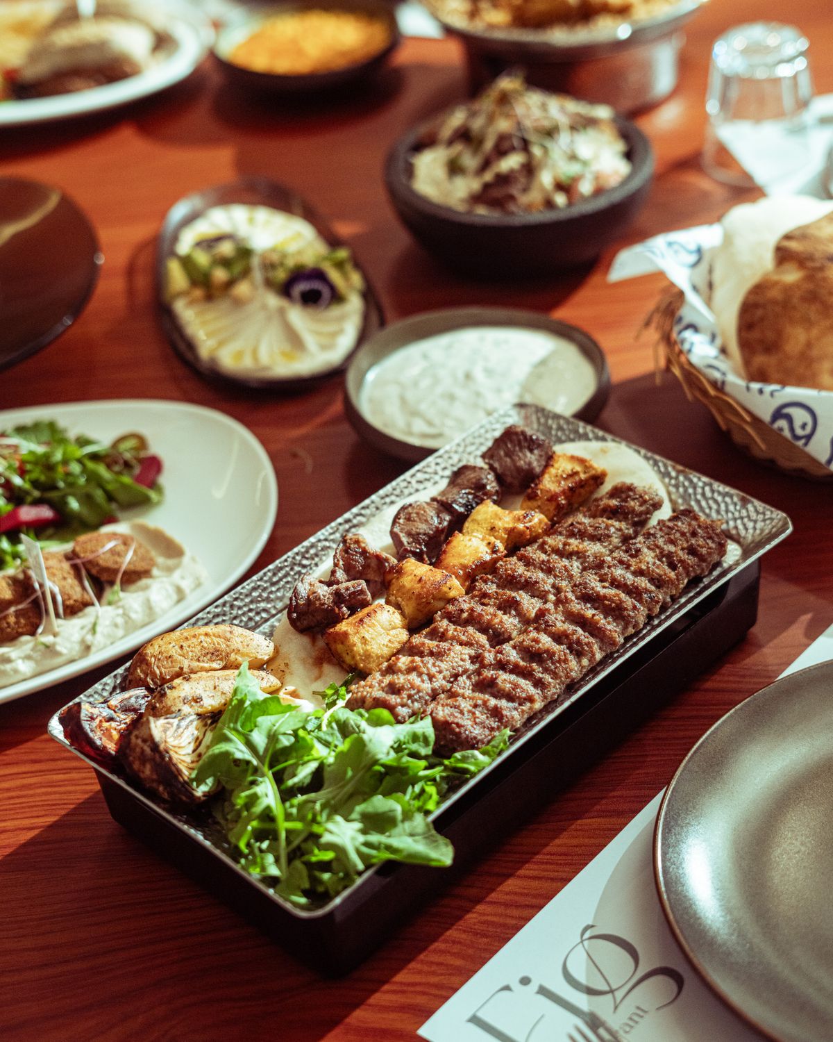 A delectable assortment of Middle Eastern dishes featuring grilled kebabs and fresh sides on a wooden table.