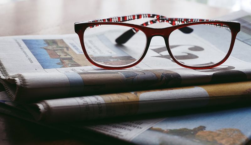 Reading glasses resting on a stack of weekend papers — photo by Suzy Hazelwood on Pexels