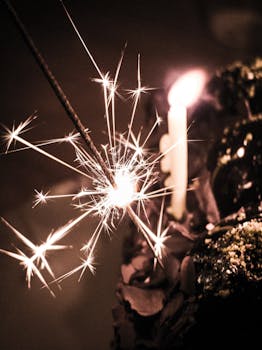 A close-up of a lit sparkler and candle on a festive birthday cake, creating a warm ambiance.