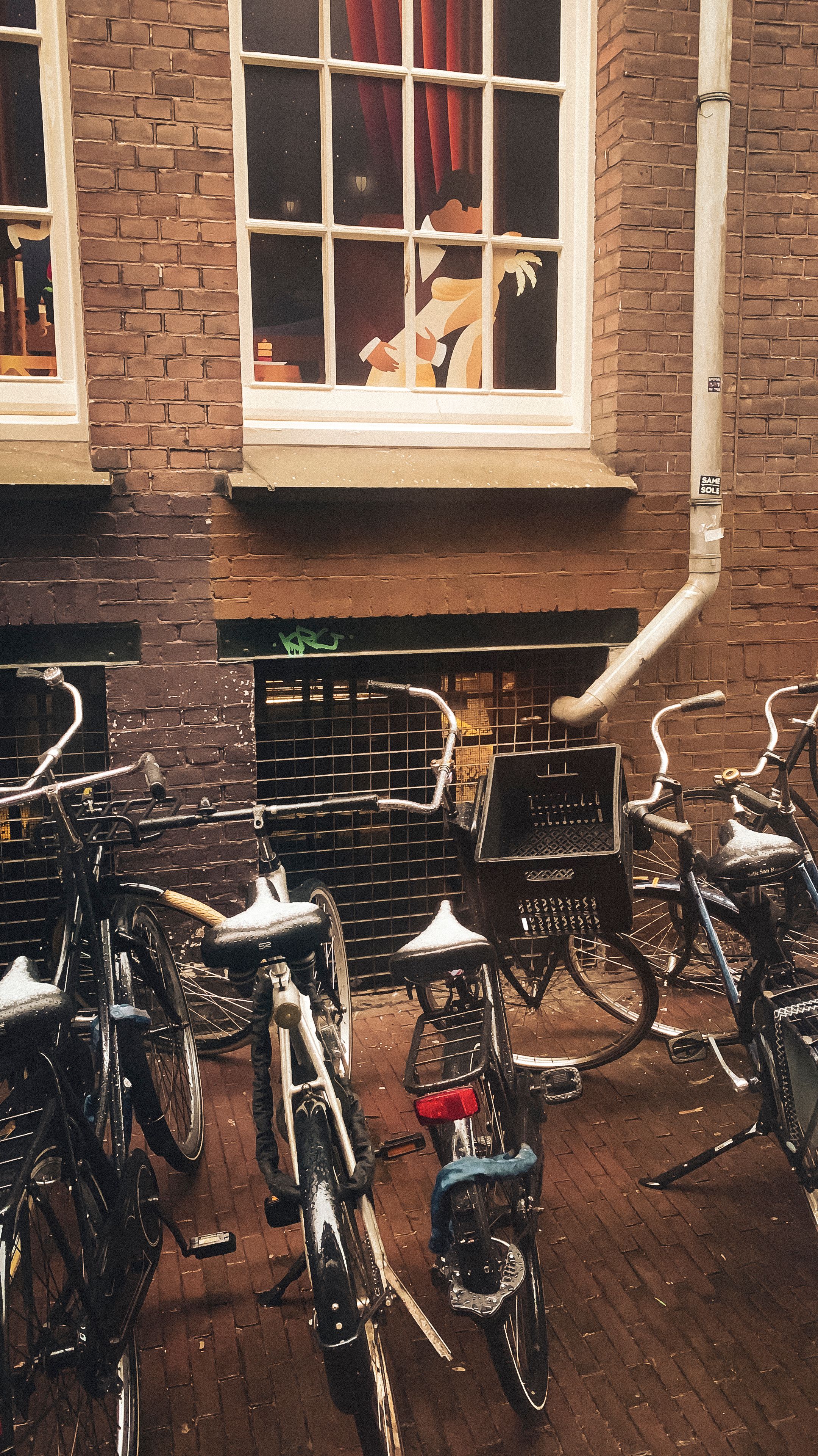 A collection of bicycles parked near a whimsical window display in Amsterdam, Netherlands.