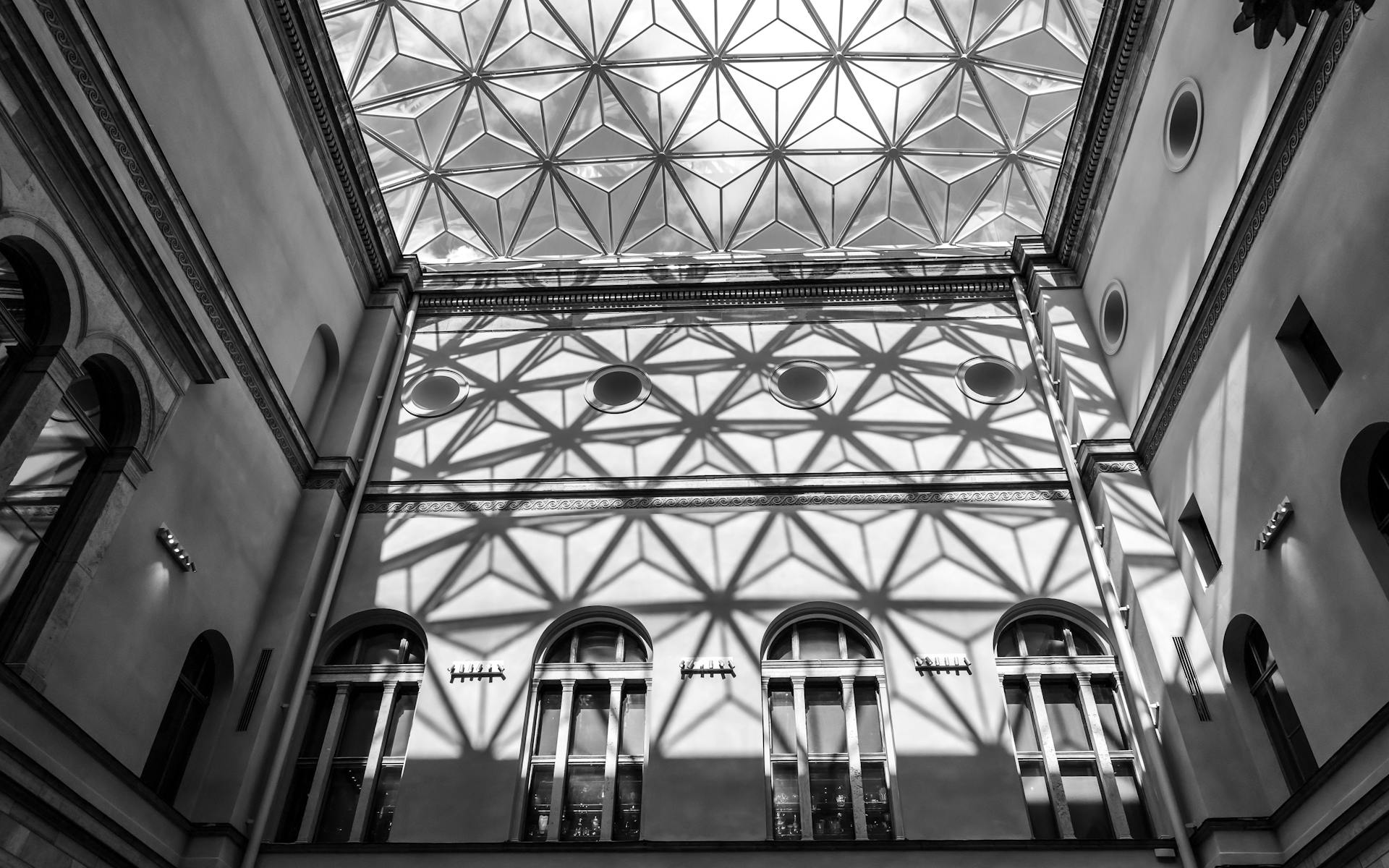 Black and white photo of geometric glass ceiling casting dramatic shadows in Stockholm atrium.