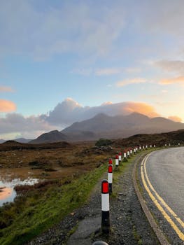 Captivating view of Scottish Highlands with a winding road and sunset sky.
