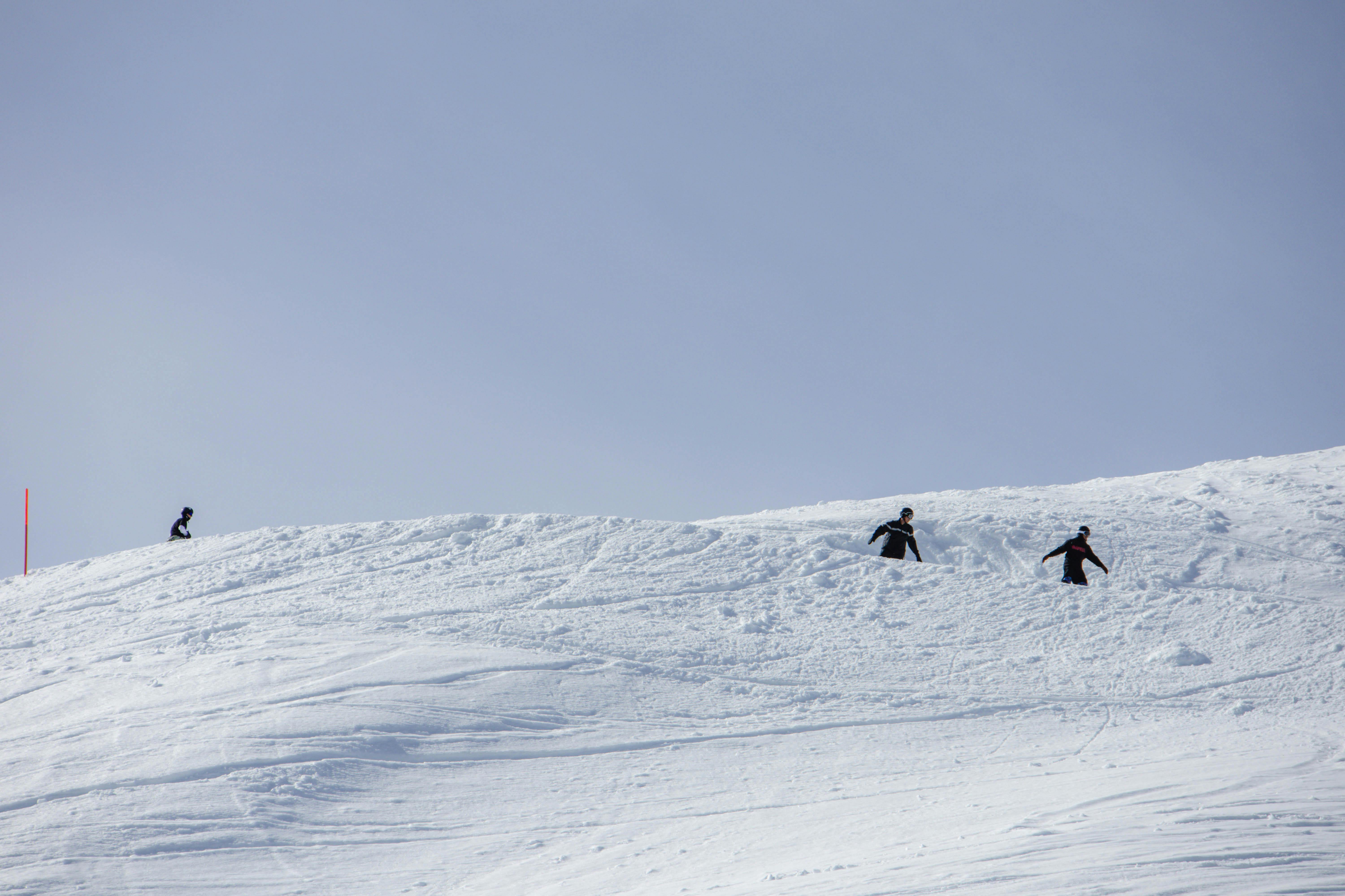 Snowboarders navigating the snowy slopes of Laax, Switzerland on a clear winter day.