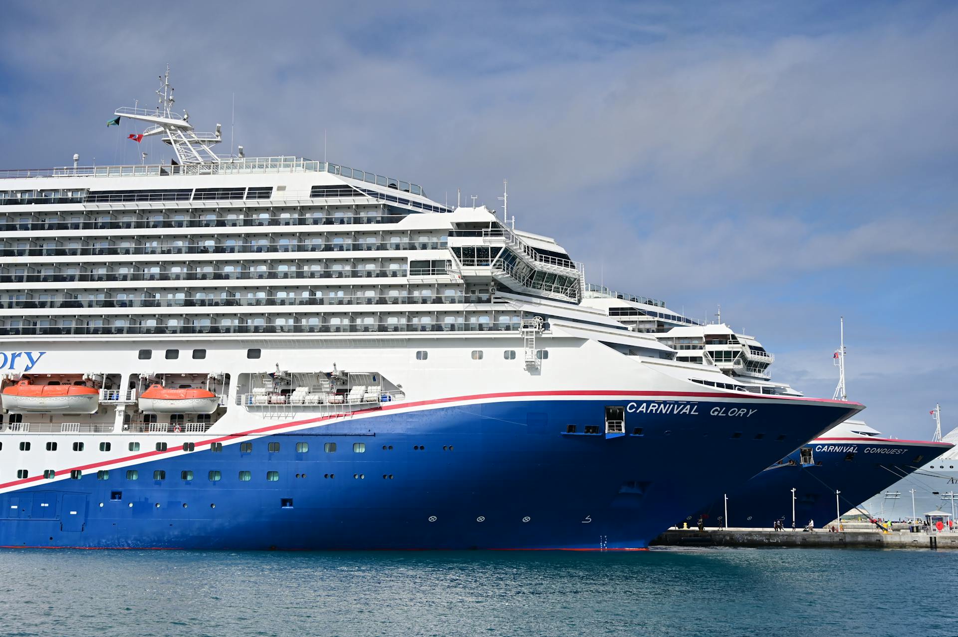 Majestic cruise ships Carnival Glory and Conquest docked at a sunny ocean port.