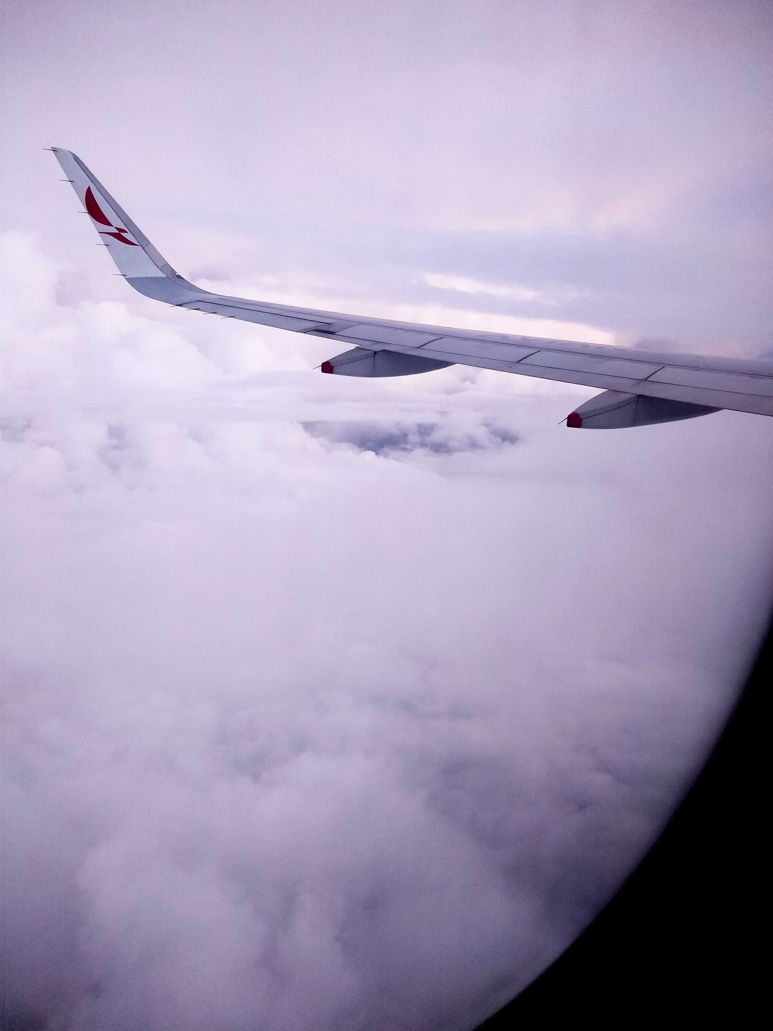 View of an airplane wing flying above the clouds, capturing travel essence.