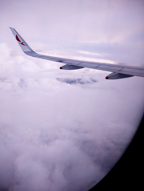 View of an airplane wing flying above the clouds, capturing travel essence.