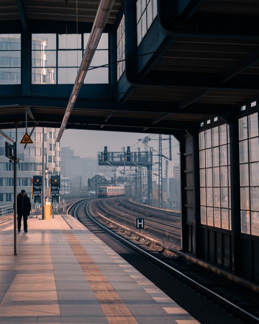 Serene view of a Berlin train station platform with urban skyline in the background.