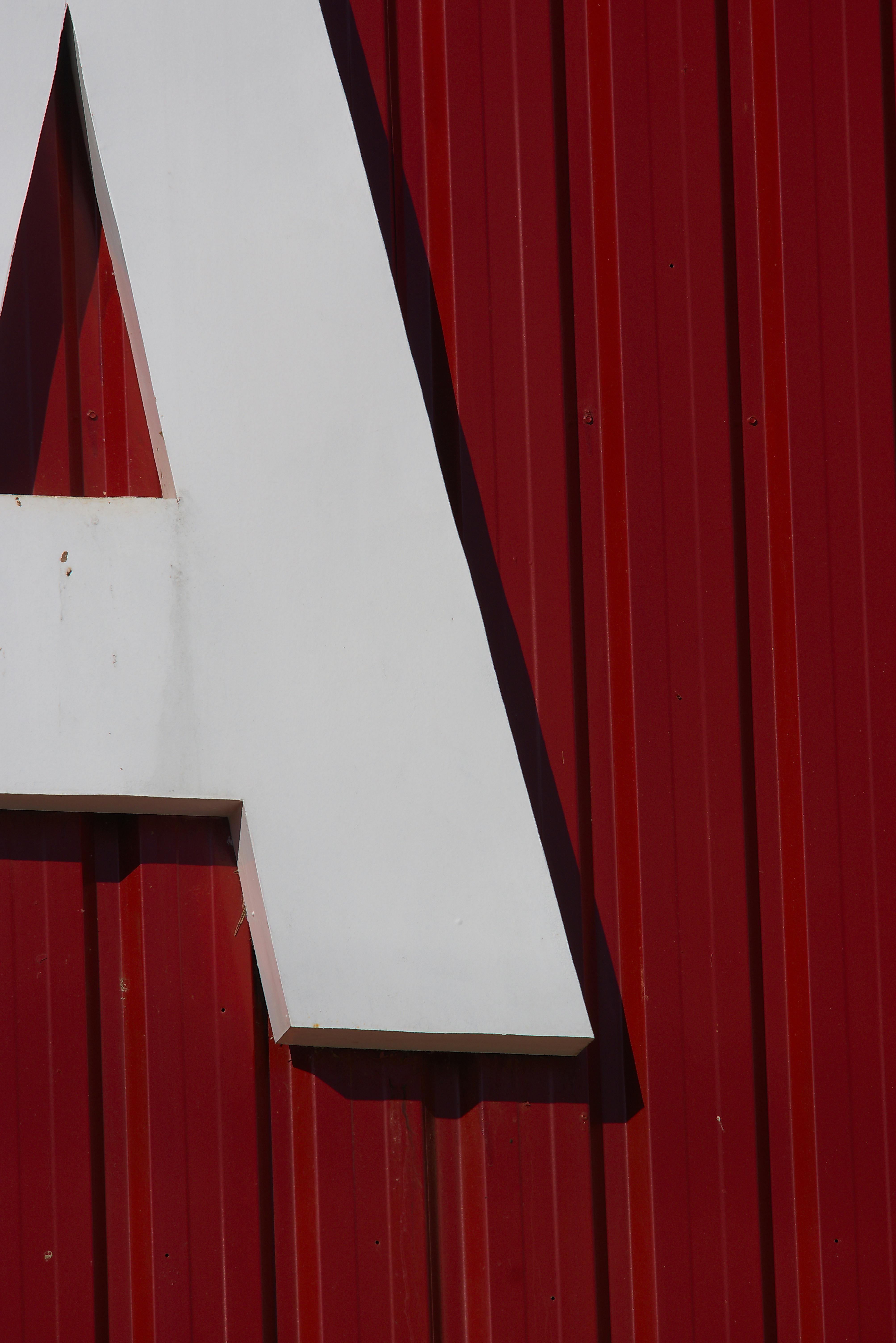 Close-up of a large white letter 'A' on a vivid red corrugated wall.