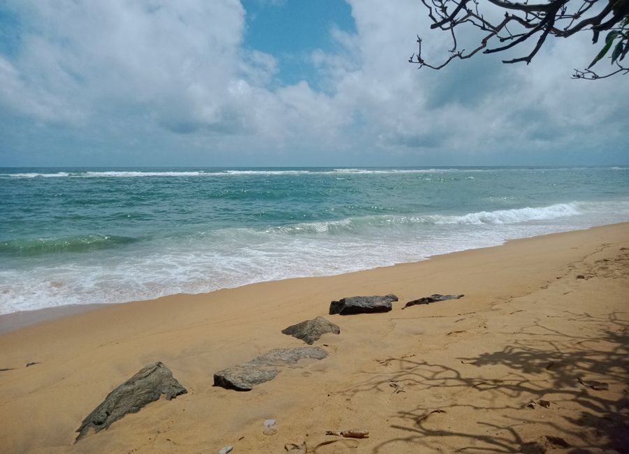 Peaceful sandy beach with gentle waves and blue sky in Colombo, Sri Lanka.