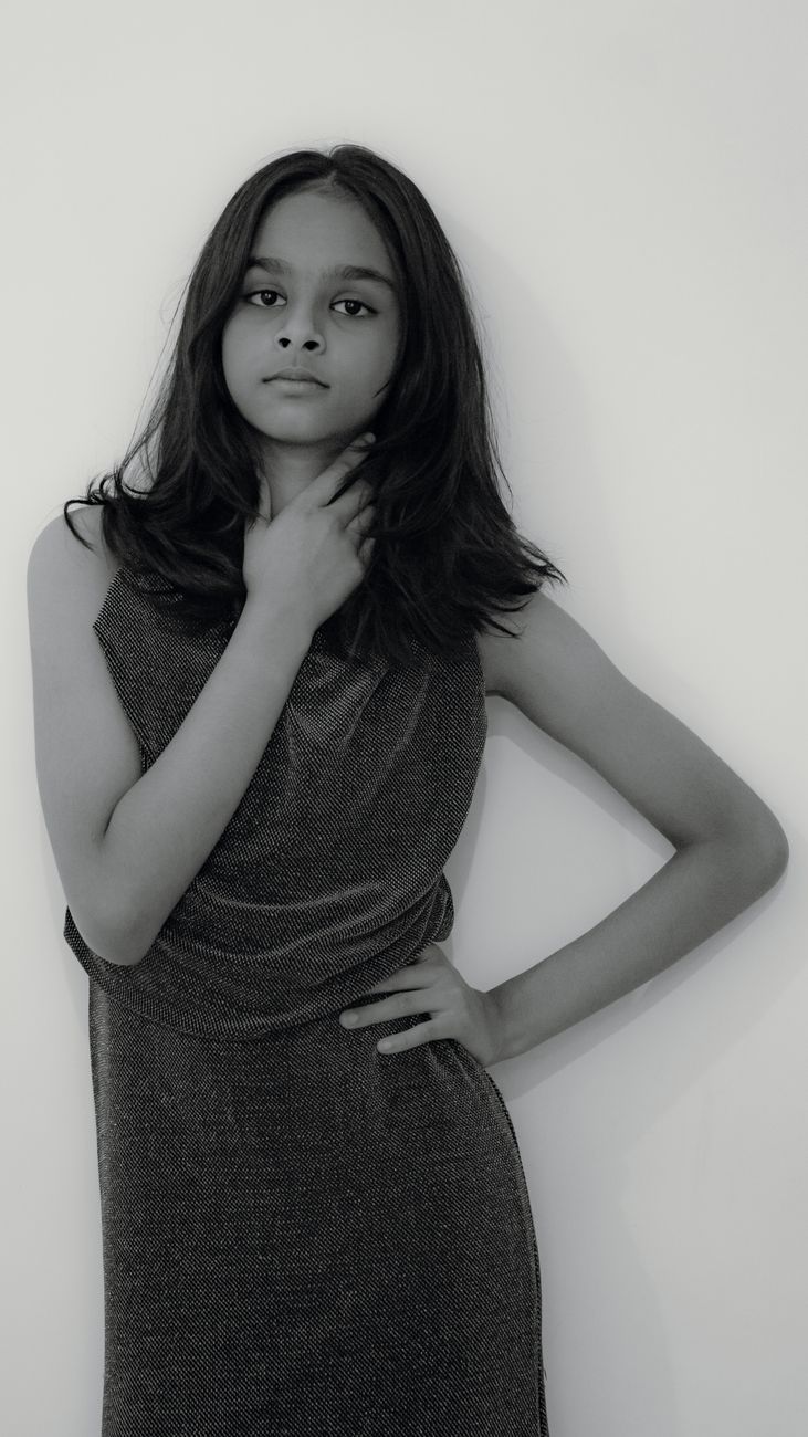 Stylish monochrome portrait of a teenage girl in a confident pose, showcasing fashion elegance.