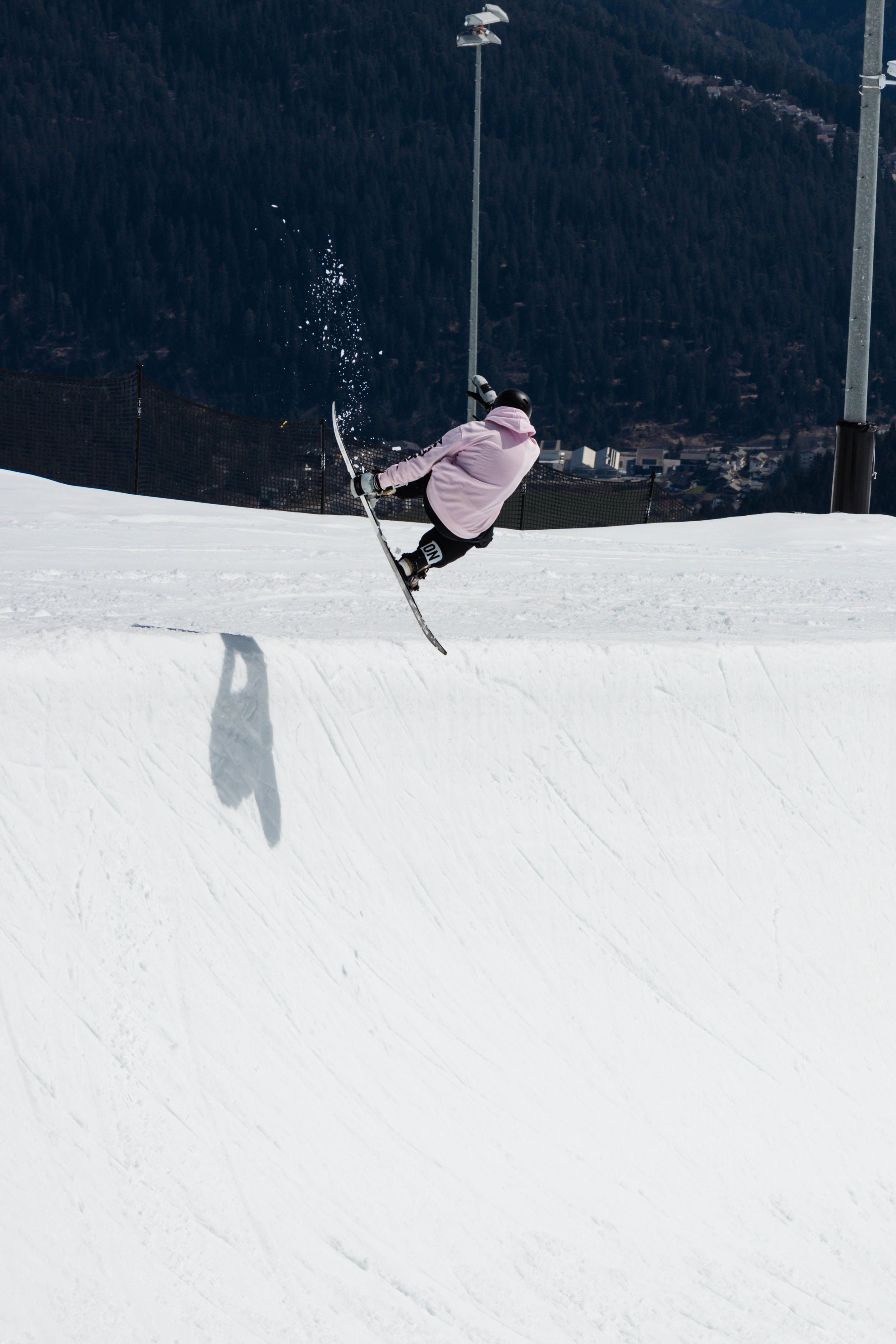 A snowboarder performs an aerial trick on a snowy slope in Laax, Switzerland, in winter.