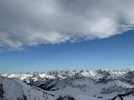 Breathtaking view of the snowy Alps mountain range under a dramatic sky, showcasing winter's serene beauty.