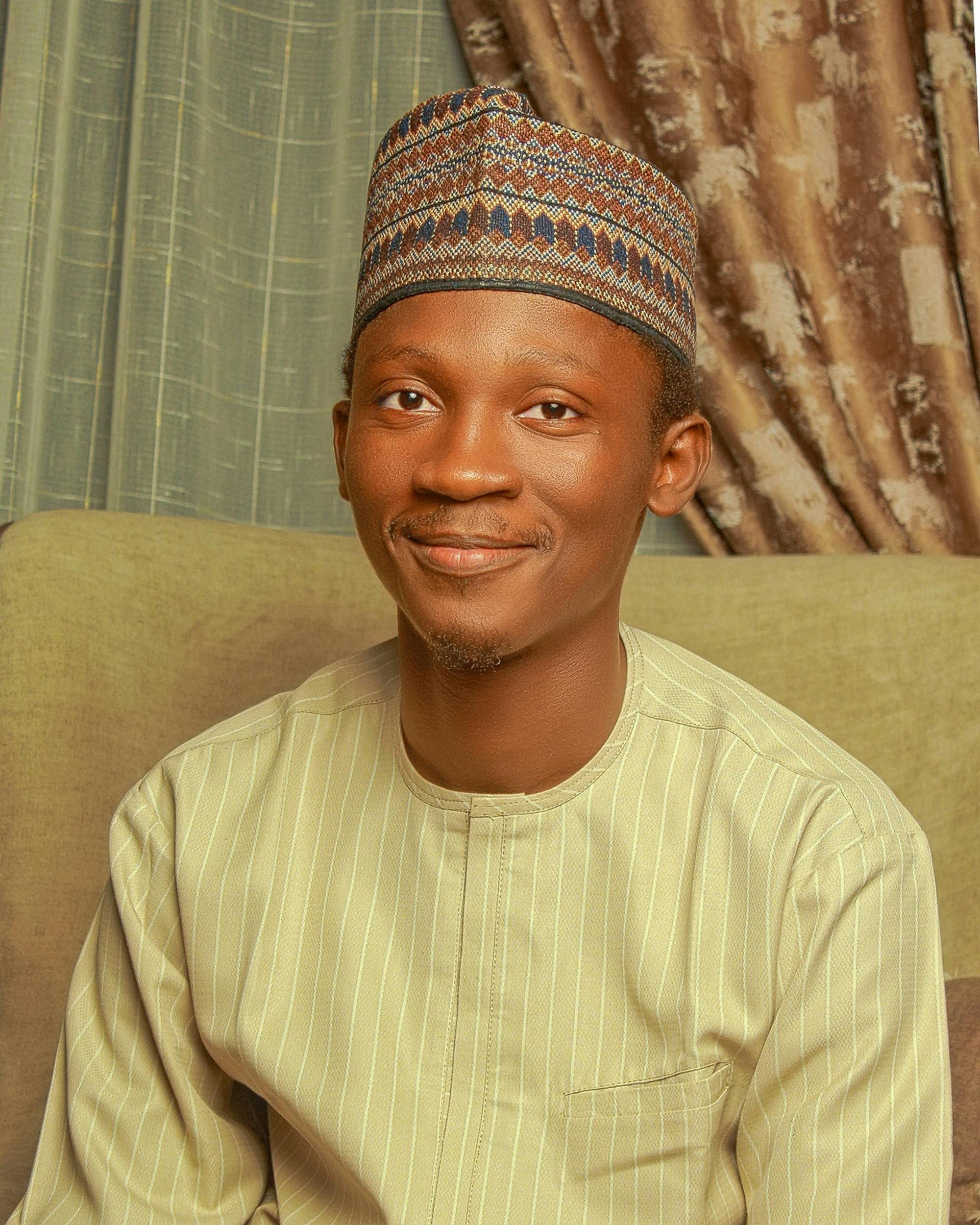 Portrait of a smiling man wearing traditional attire and hat indoors.