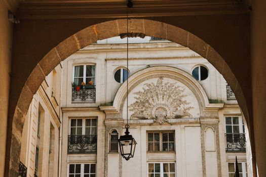 View of ornate Parisian building facade framed by an archway with a decorative lantern.