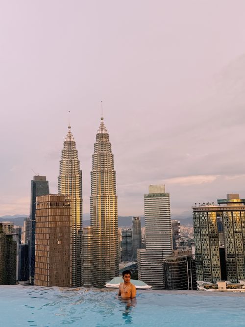 Free A serene moment in an infinity pool with a stunning view of Kuala Lumpur's skyline and Petronas Towers. Stock Photo