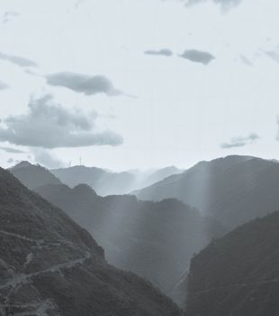 Breathtaking view of misty mountains in Hà Giang, Vietnam, with sunlight piercing through clouds.