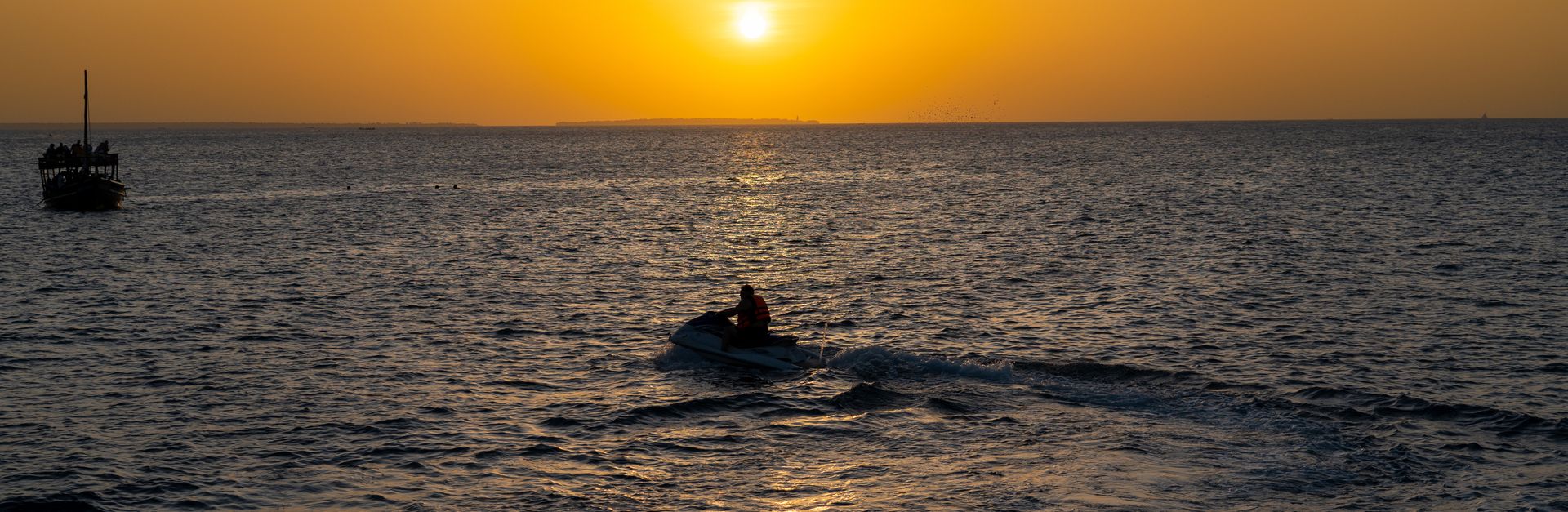 Vivid sunset over the Indian Ocean in Zanzibar with a jet ski silhouette.