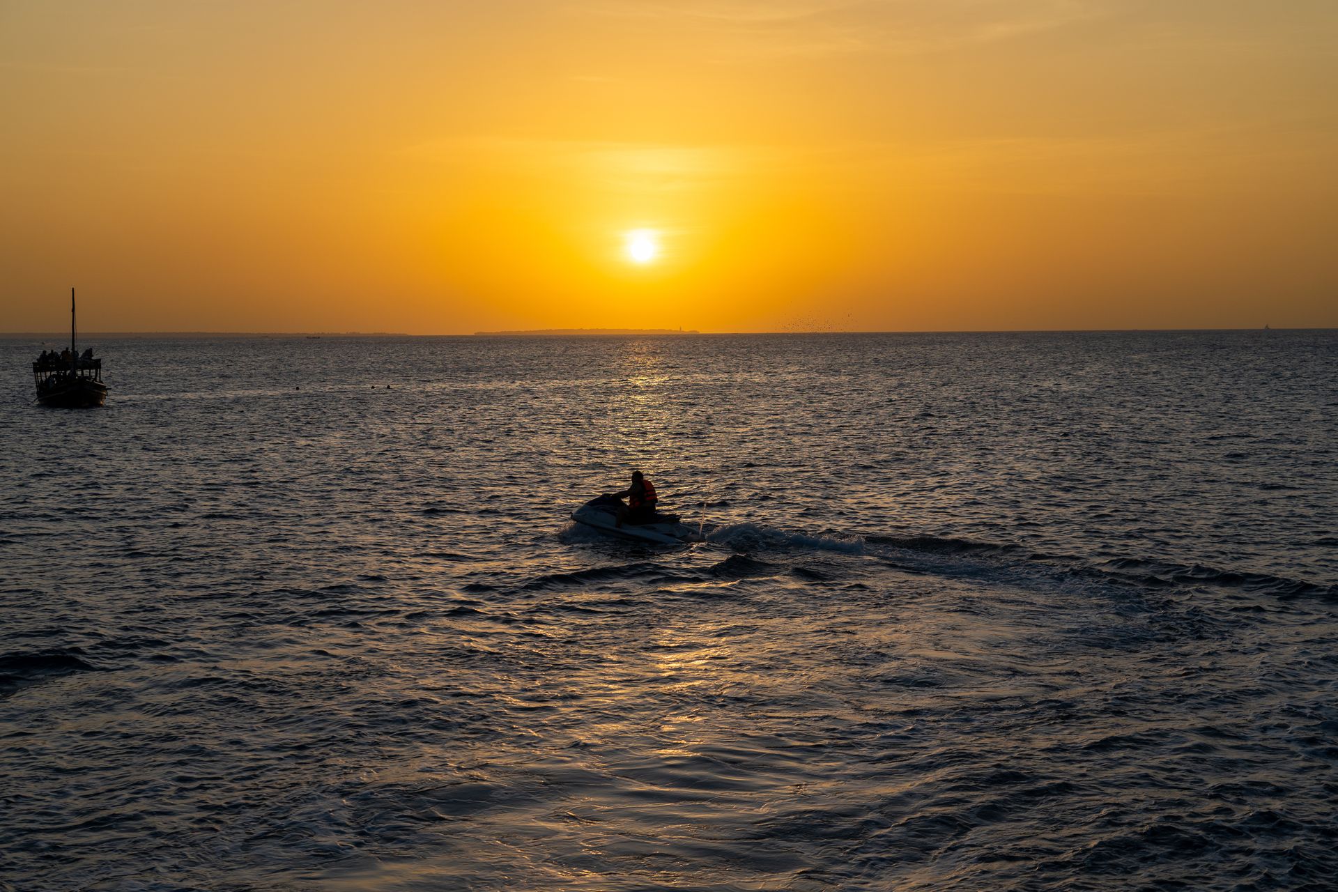 Vivid sunset over the Indian Ocean in Zanzibar with a jet ski silhouette.