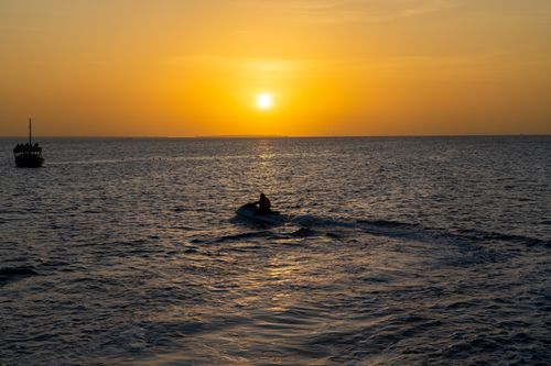 Free Vivid sunset over the Indian Ocean in Zanzibar with a jet ski silhouette. Stock Photo