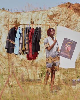 A fashionable display of clothing outdoors with an artistic poster backdrop.