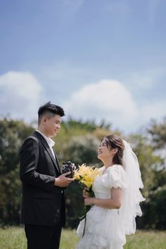 A bride and groom share a moment outdoors, with the groom holding a vintage camera.