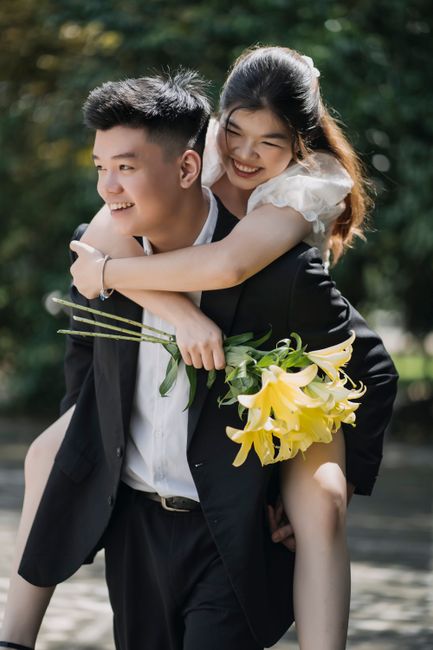 Young couple enjoying piggyback ride with yellow flowers outdoors.