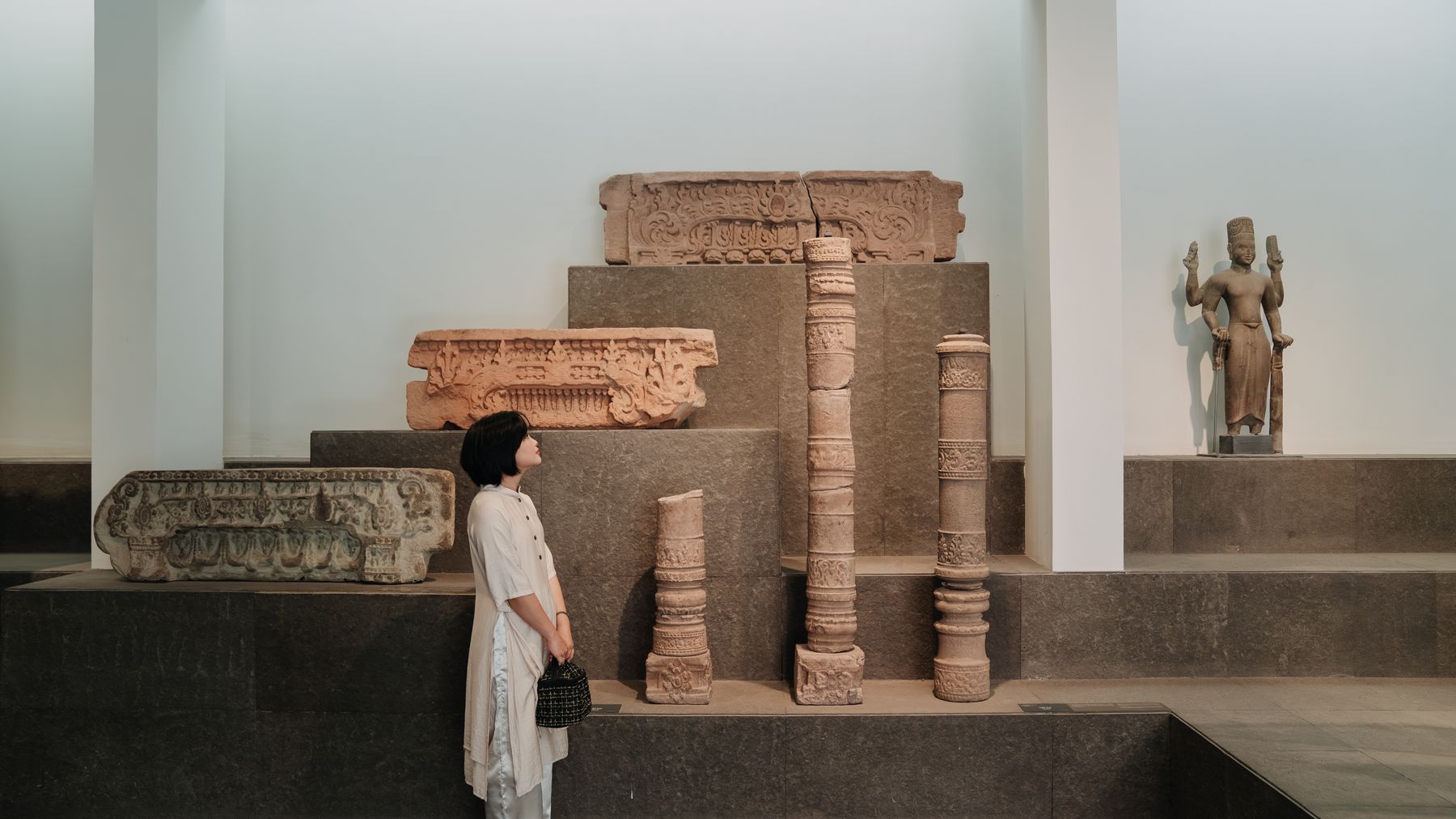 A woman observes historical artefacts in a well-lit museum exhibit.