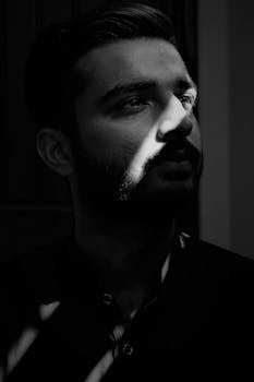 A striking black and white portrait of a man with light and shadow play accentuating his facial features.