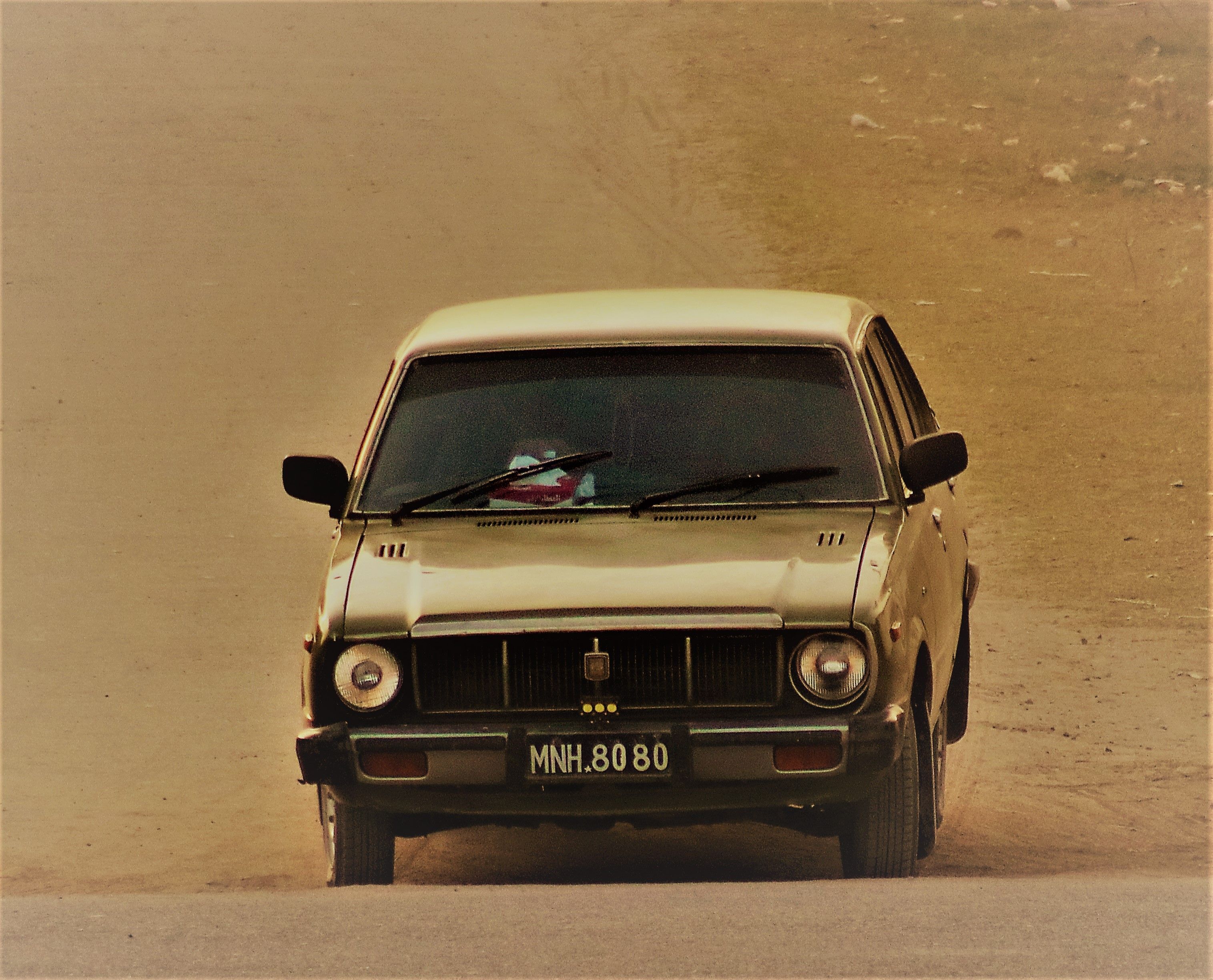 Vintage car driving on a dusty road in Lahore, Pakistan with a classic charm.